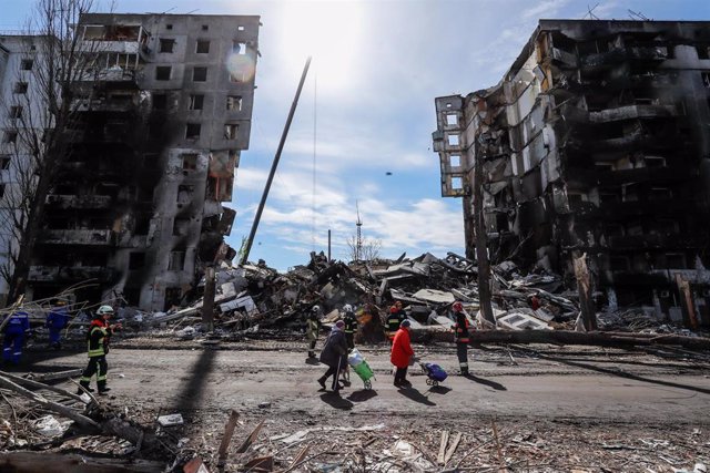 Residents walk past a residential building destroyed by Russian airstrikes in Borodyanka, Bucha Raion of Kyiv Oblast.